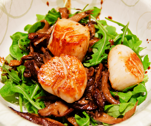Seared scallops on a bed of baby greens with sauteed wild mushrooms.